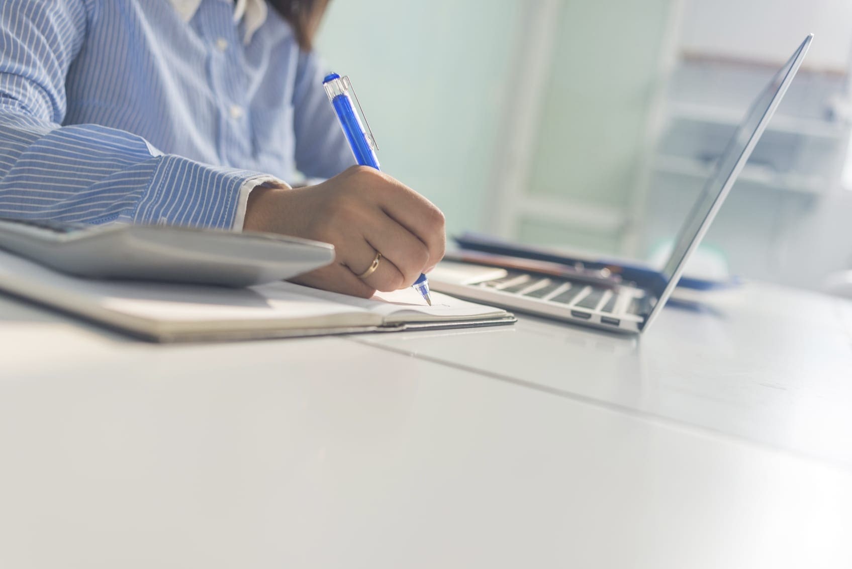 Close-up of businesswoman hand writing notes in her office