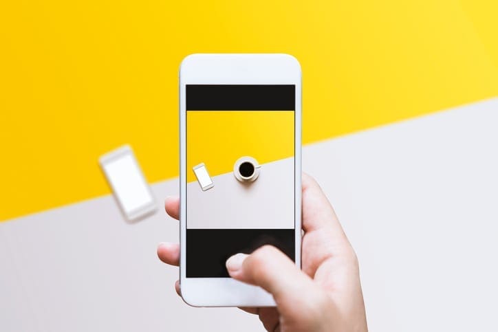 Hand photographing food on color block background with mobile phone